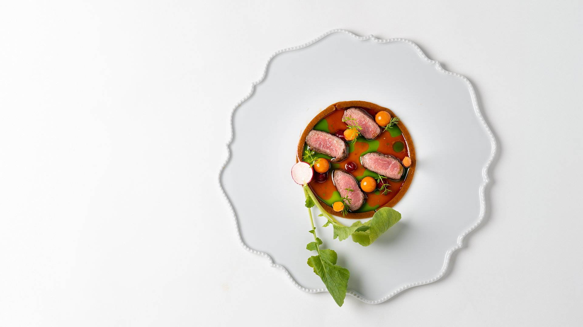 Piatto creativo con carne scottata, ortaggi e riduzione al Ristorante Amistà