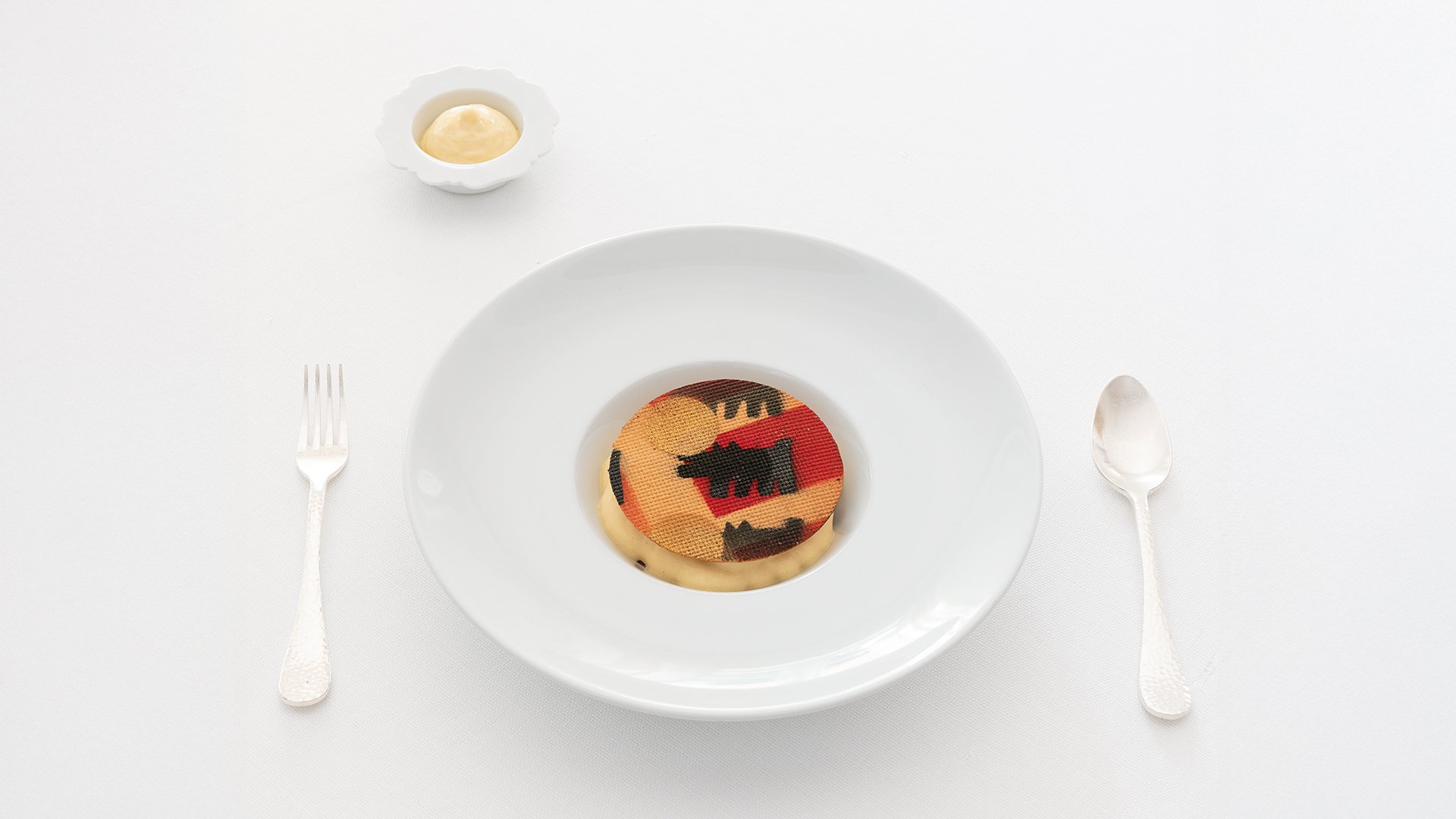 Portata artistica con cialda decorata e crema, presentata su piatto bianco elegante
