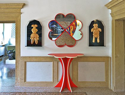 Consolle rossa e specchio a quadrifoglio di Alessandro Mendini, con nicchie laterali e sculture decorative su parete in pietra