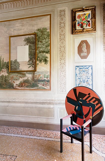 Sedia d’artista con schienale rotondo decorata da motivi geometrici su fondo rosso nella Sala Paolini