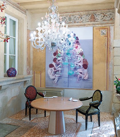 Sala pomodoro con lampadario in vetro di Murano, tavolo rotondo e opera di Vanessa Beecroft alle pareti