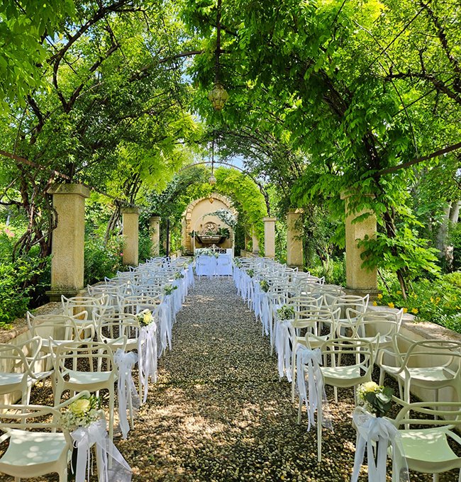 Cerimonia di matrimonio all’aperto nel giardino con archi fioriti