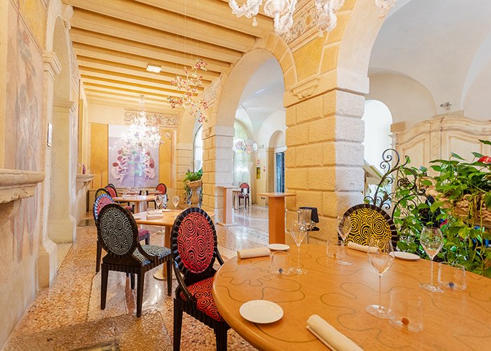 Sala da pranzo con sedie artistiche e affreschi sulle pareti