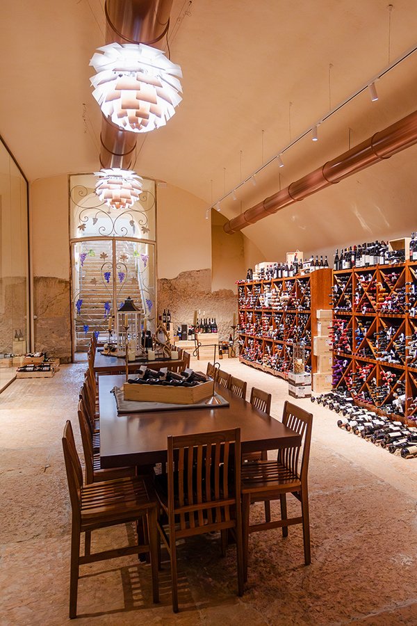 Tavolo degustazione e pareti con bottiglie di vino d’annata