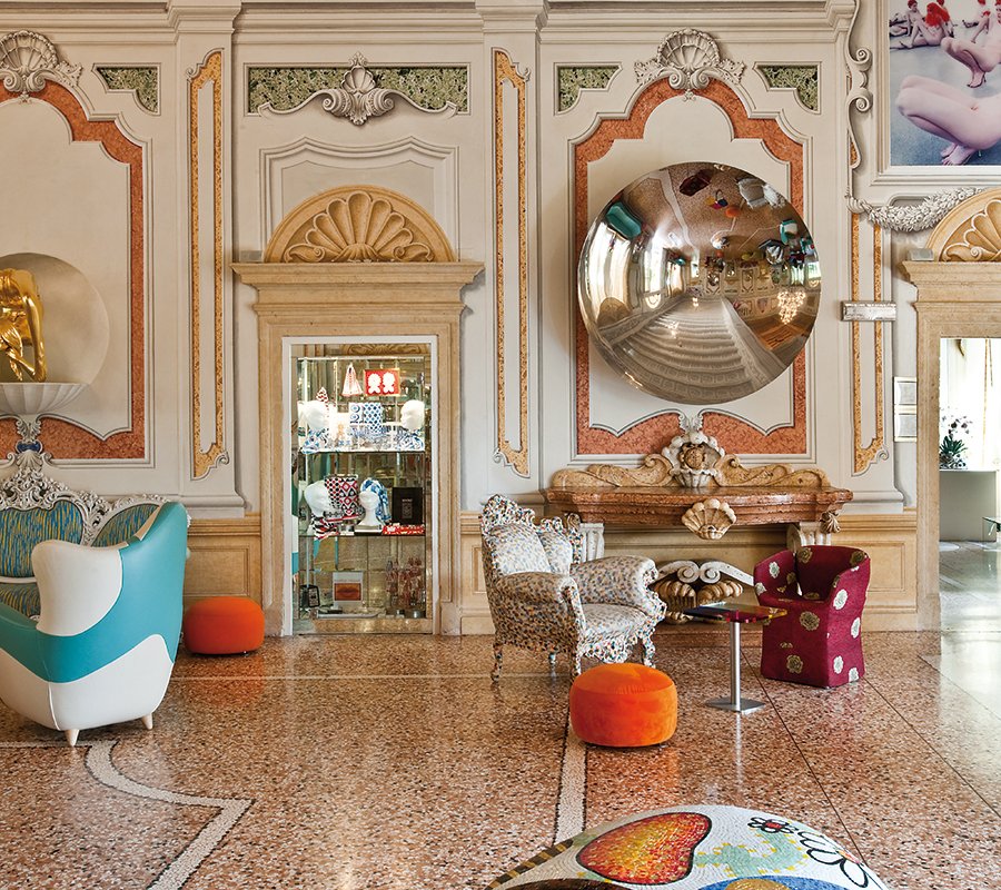 Sala della hall del Byblos Art Hotel con specchio concavo di Anish Kapoor, poltrone colorate e design eclettico.