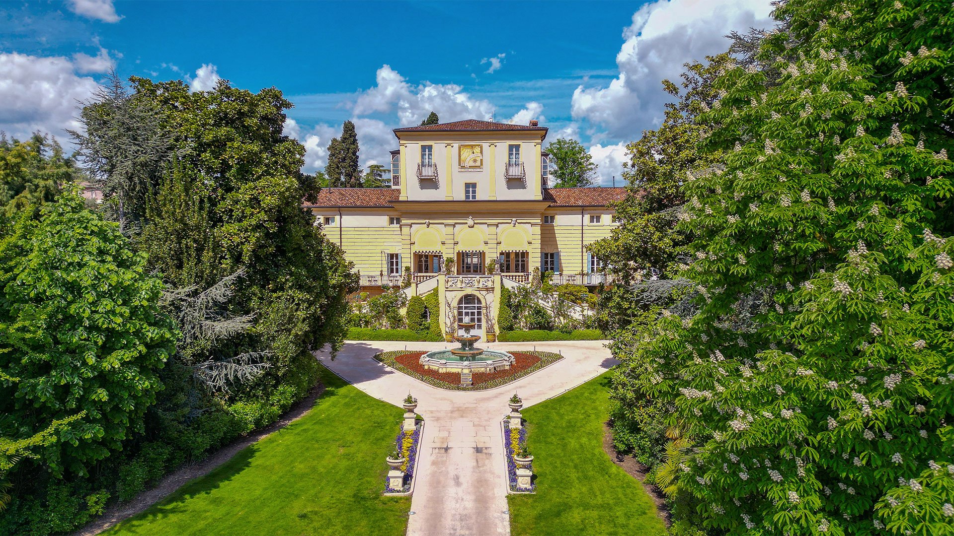 Vista panoramica della facciata principale del Byblos Art Hotel Villa Amistà con giardino e fontana centrale